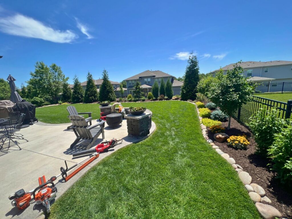 A landscaped back yard with a stretch of green grass and flowers.