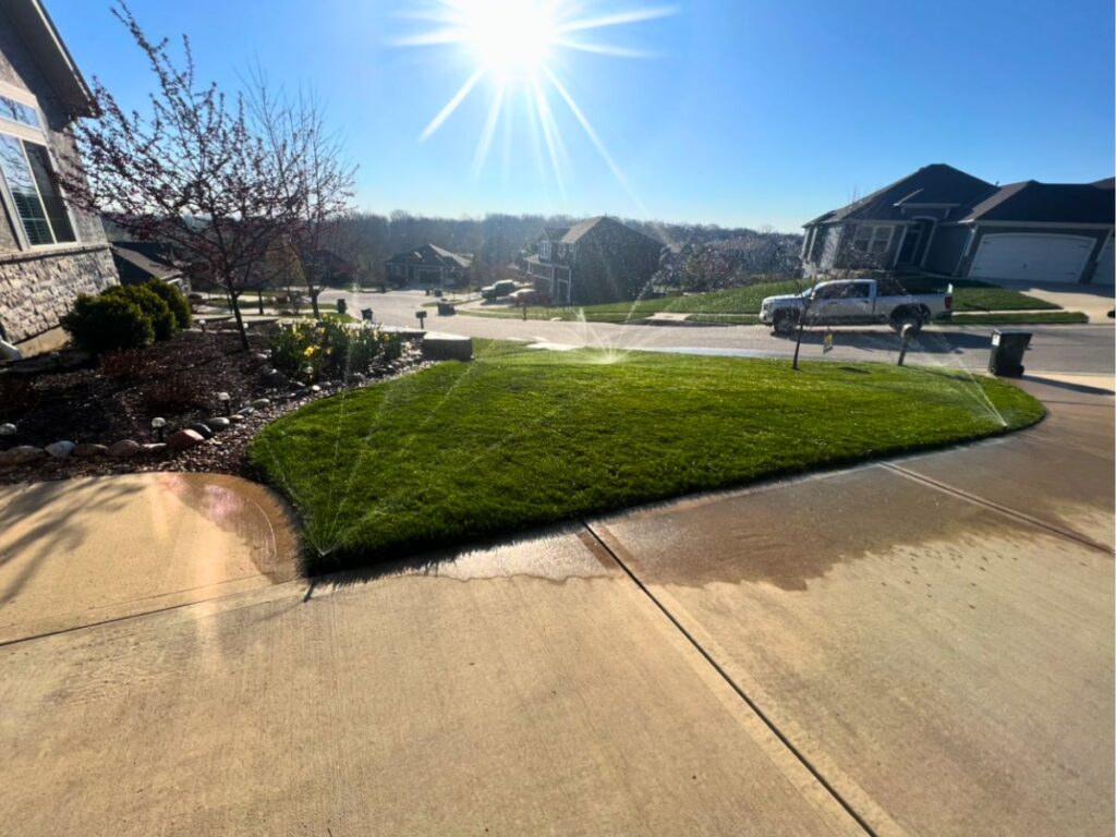 An in-ground sprinkler system waters a lush green yard in suburban Kansas City.